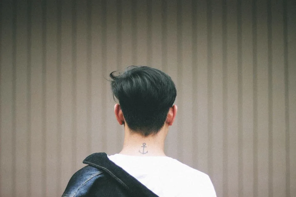 Man seen from behind, alone, looking at a quiet wall